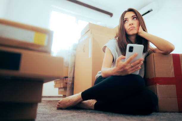 istock Unhappy Woman Checking Phone Surrounded by Cardboard Boxed 1413510431