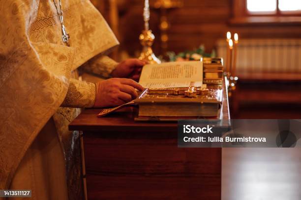 Cropped Photo Of Priest In Golden Ceremonial Cassock Stand At Lectern With Books Reading Pray Book In Orthodox Church Stock Photo - Download Image Now