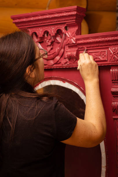 mulher com armário estampado de pintura de pincel com ornamentos esculpidos em vermelho. processo de patinação de móveis. reutilização ecológica. coisas velhas ganhando vida nova - patination - fotografias e filmes do acervo