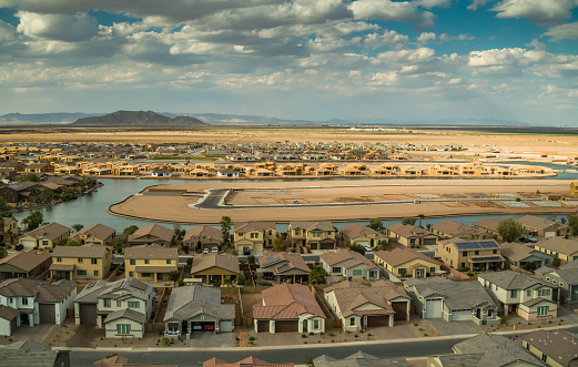 Panoramic aerial shot of Maricopa, Arizona, flying over a growing housing development being built around an artificial lake.