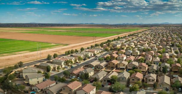 Panoramic Aerial Shot of Suburban Housing and Farmland in Maricopa, Arizona Aerial shot of a housing development bordering farmland in Maricopa, Arizona. urban sprawl stock pictures, royalty-free photos & images