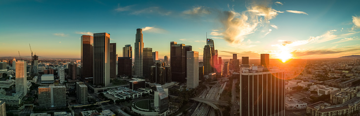 Drone panorama of Downtown Los Angeles on a summer evening with a dramatic and colorful sunset behind the skyline of the financial district.