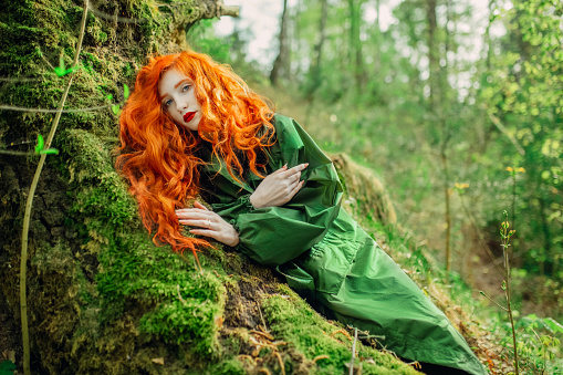 Redhead woman in raincoat on background of wet forest. Save earth. Green summer trees. Protection of nature. Tourist travel in rain coat. Save planet eco concept. Spring nature. Moss on tree