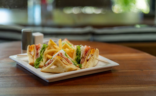 Club sandwich setting on wooden table with blur background.