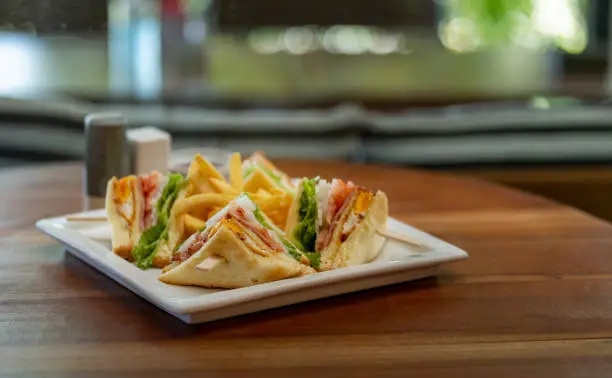 Club sandwich setting on wooden table with blur background.