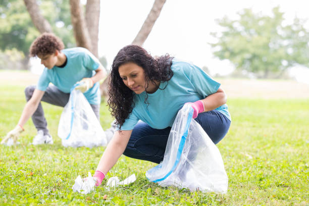 istock Volunteers kneels down to collect trash off grass 1413520676