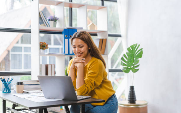 istock Smiling young asian student studying on online courses improving professional knowledge or preparing for exam, video call online via laptop at desk. 1413521518