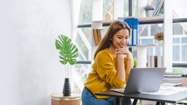 istock Smiling young asian student studying on online courses improving professional knowledge or preparing for exam, video call online via laptop at desk. 1413521525