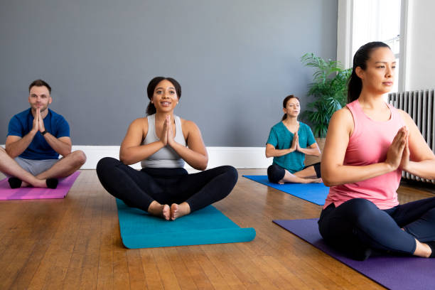 istock Athletic adults practicing yoga together in local gym 1413522990