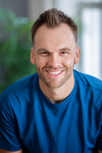 Happy young adult man smiles while wearing athletic clothing