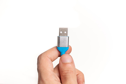 Image of human hand holding blue USB cable isolated on white background with copy space