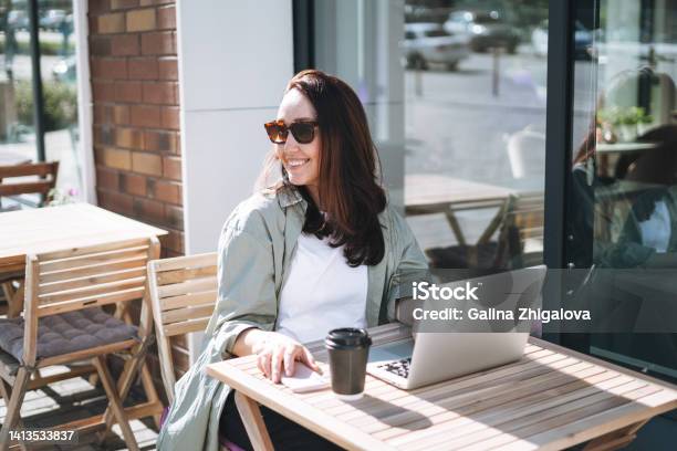 Adult Smiling Brunette Business Woman Forty Years In Stylish Shirt Working On Laptop In Cafe At City Street Stock Photo - Download Image Now