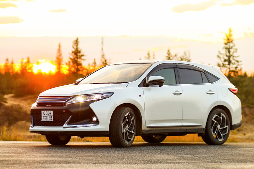 Novyy Urengoy, Russia - July 26, 2022: White Japanese crossover Toyota Harrier at the background of sunset.