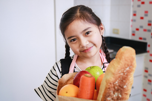 Portrait of an Asian cute kid girl in a kitchen at home. Leisure activity