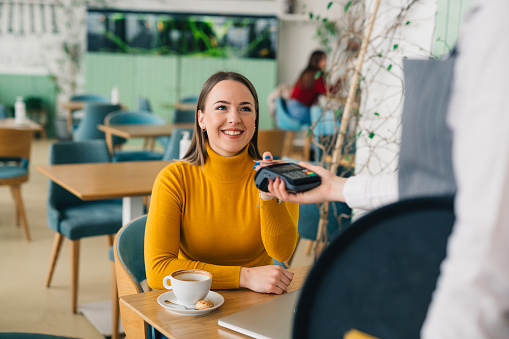 woman paying c contactless with credit card in cafe