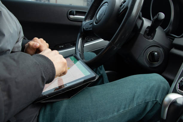 istock sales representative driving his car with a tablet in his hands, hands on the steering wheel in the car 1413541672