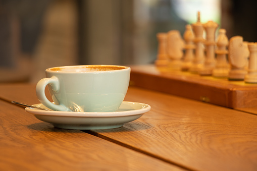 cup of coffee near chess on a wooden table, playing chess over a cup of coffee on a break, coffee break