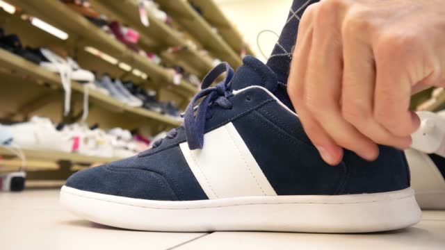 Close-up of a sport shoe in a shoe store and a man trying it on