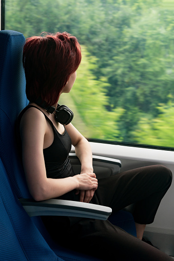 young woman in a moving suburban train looks out the window