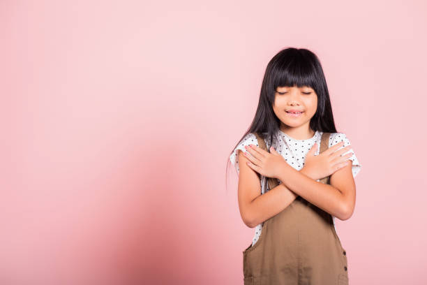 istock Asian little kid 10 years old doing grateful gesture and closed eyes 1413548855