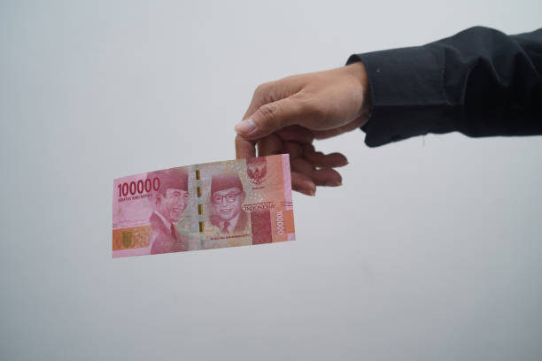 istock One hundred thousand rupiah dropped from man's hand on white background 1413549234