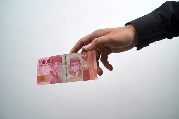 istock One hundred thousand rupiah dropped from man's hand on white background 1413549237