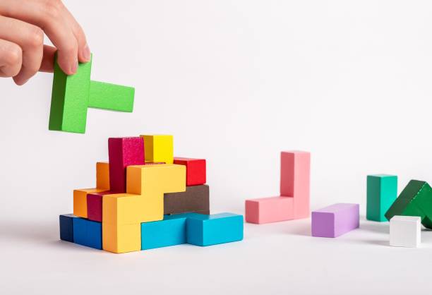 istock Hand assembling tetris puzzle, searching appropriate place for wooden block. Construction, formation concept. Finding solution to problem. Logical thinking, reasoning strategy development. 1413549949