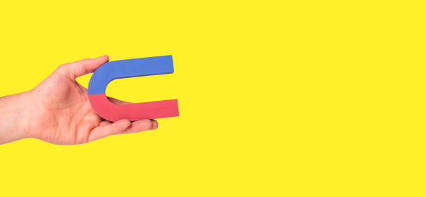 istock Banner with hand holding horseshoe magnet on yellow background. Copy space. Attraction concept. 1413550747