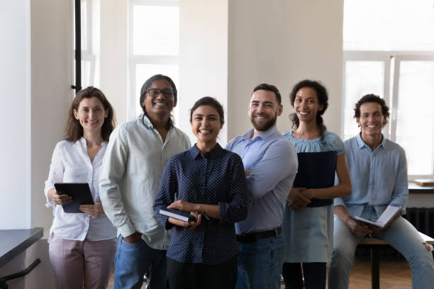 istock Group of happy diverse office employees pose at workplace 1413550842