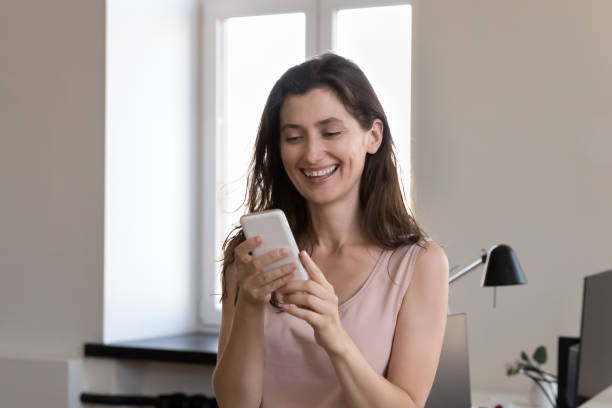 istock Woman office employee standing at workplace using smartphone 1413550855