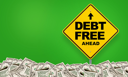 Yellow Debt Free ahead sign on green background and dollars