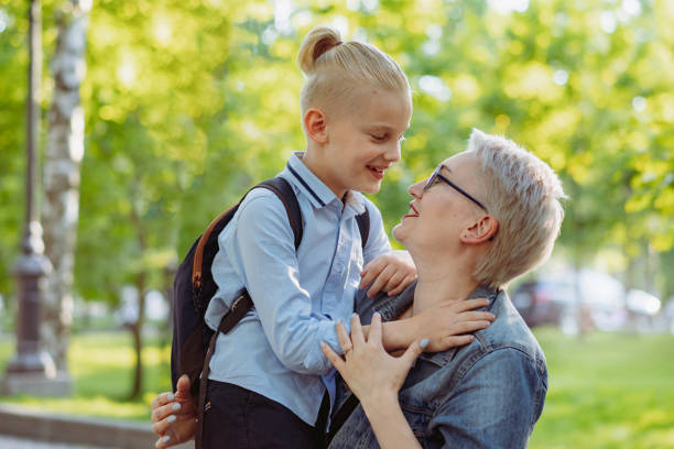 istock cute caucasian blonde boy with ponytail going to school. Mother having a conversation with child 1413552485