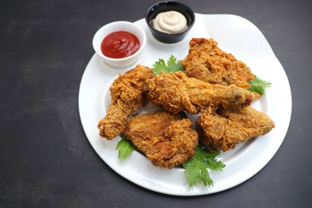 istock Fresh, hot, crispy deep fried chicken served on a white plate with tomato ketchup and mayonnaise. Chicken snack, hot fried chicken wings. Fast food over moody dark black background with copy space. 1413553180
