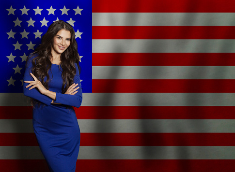 Friendly young adult woman against American flag background