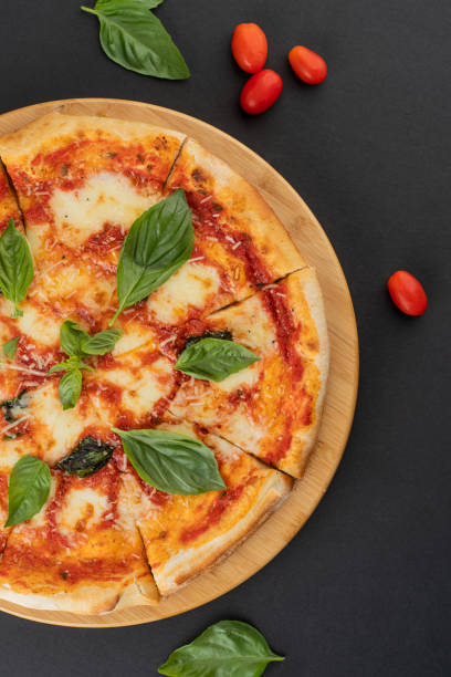 istock Italian food: delicious pizza with mozzarella and cherry tomatoes shot from above on dark grey background 1413553735
