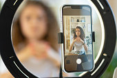 Young curly female blogger recording video at table at home