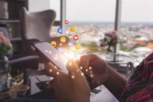 Young man using smartphone sending emojis. Mobile smartphone sending text messages emoji emoticon. stock photo