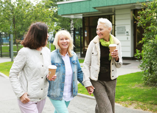 istock Three cheerful pensioners are walking in the park, having fun talking and drinking coffee. 1413554931
