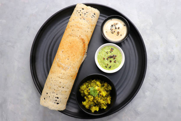 crispy masala dosa is a popular south indian food item served with tomato chutney, coconut chutney, spicy potato masala, or aloo ki sabzi and sambar. copy space. crunchy rice crepes. - dosa imagens e fotografias de stock