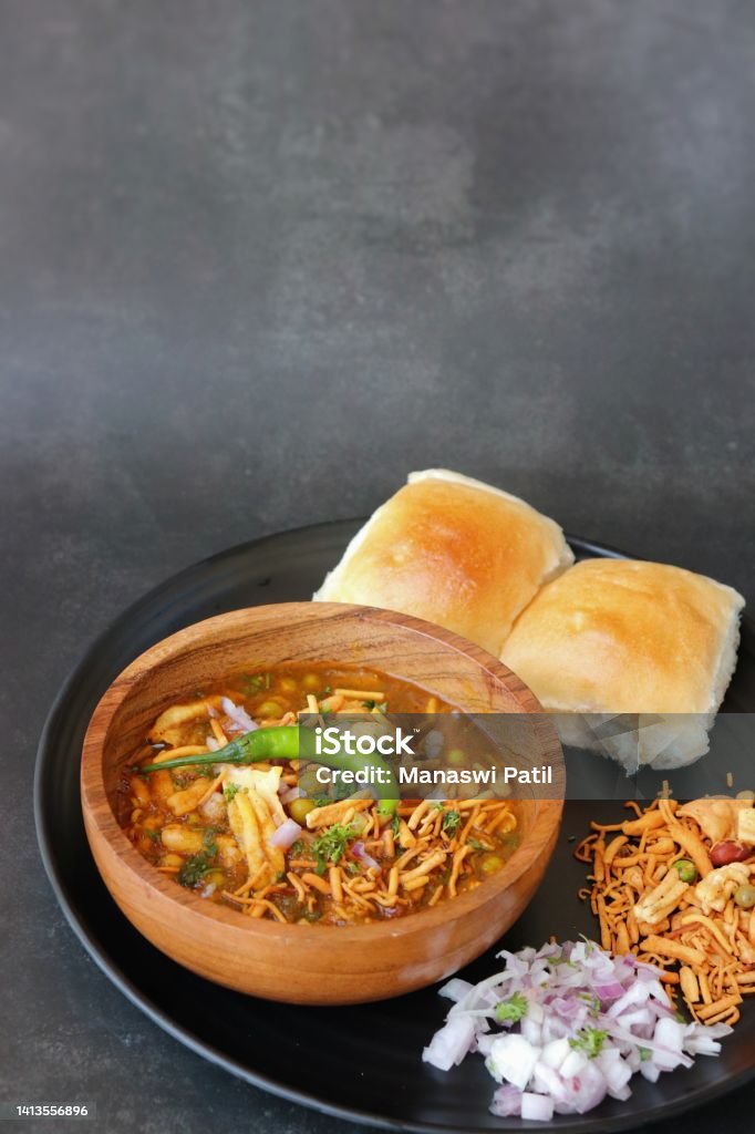 Spicy Misal Pav or usal Pav is a traditional snack or Chaat food from Maharashtra, India. Served with chopped onion, lemon wedges and farsan. Selective focus with copy space Bread Stock Photo