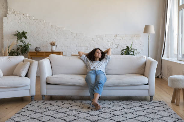 szczęśliwa troskliwa latynoska kobieta odpoczywająca na wygodnej kanapie w domu - fizyczne osłabienie zdjęcia i obrazy z banku zdjęć