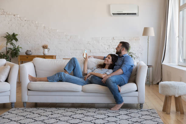 happy millennial couple of homeowners enjoying cool conditioned air - confortável imagens e fotografias de stock