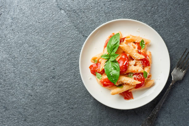 istock Penne pasta with cherry tomatoes on grey background top view with copy space 1413558593