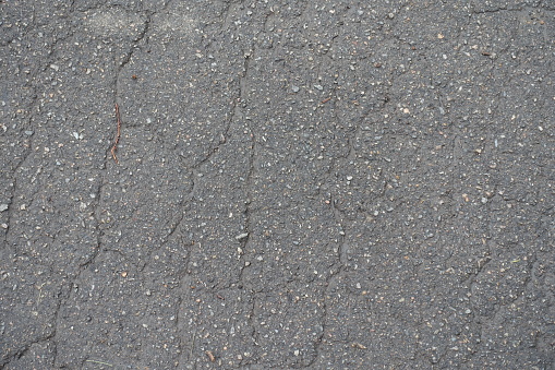 Dirty and wet old asphalt with numerous cracks