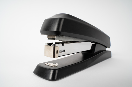 Close up of a black paper stapler on a white background