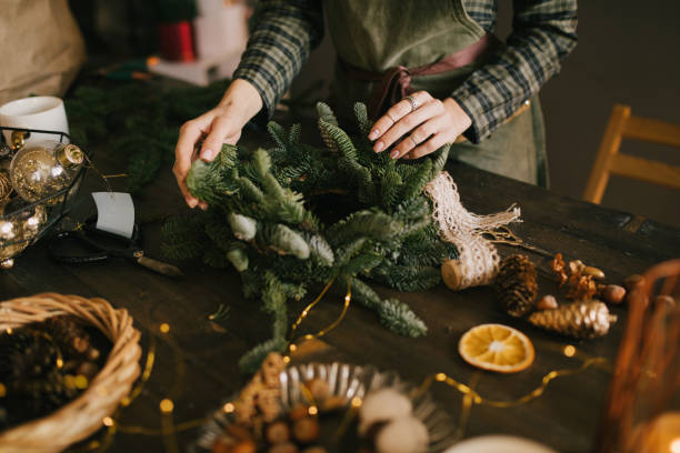 istock Millennial woman making Christmas wreath using natural pine branches and festive decorations in workshop. 1413565228