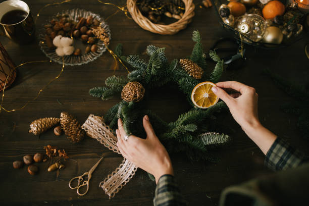 istock Millennial woman making Christmas wreath using natural pine branches and festive decorations in workshop. 1413565234