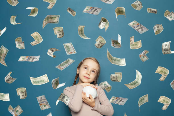 istock Happy attractive little kid on falling money rain on blue background 1413565464