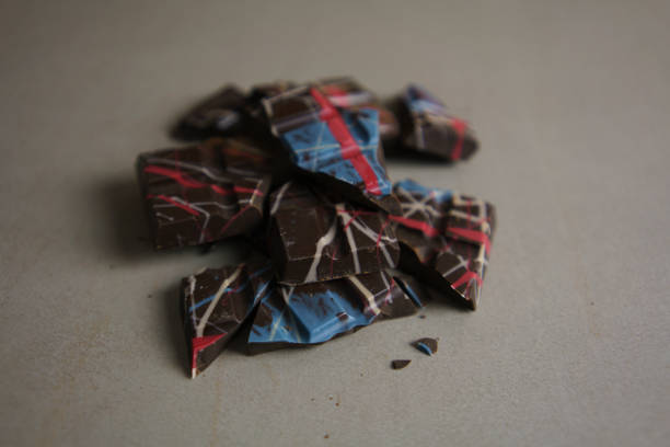 Shards and broken pieces of dark chocolate. The chocolate features colourful swirls embedded throughout.