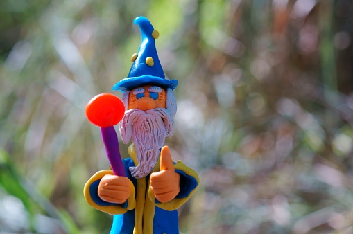 A toy wizard with a staff on a colored background. Fabulous scenery.